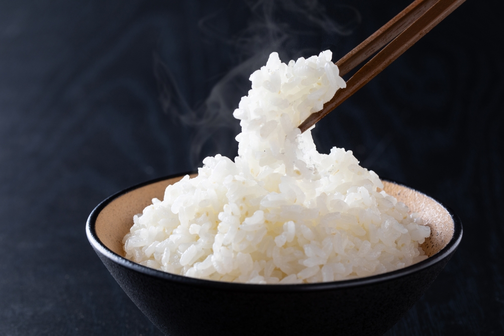 湯気の立つごはんを箸で持ち上げる様子、こんにゃく米を混ぜて炊いたごはんのイメージ